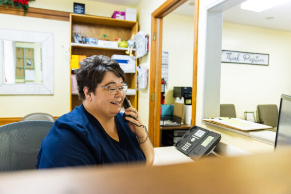 Receptionist Tammy helping a patient on the phone at her desk.