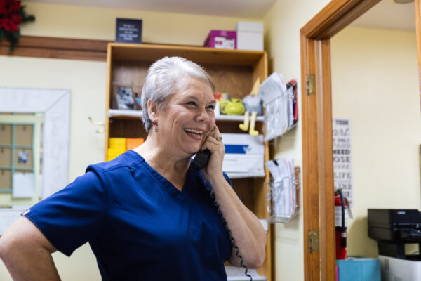 Office manager Regina Lambert speaking on the phone and smiling.